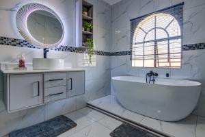 a bathroom with a tub and a sink and a mirror at Kempton kingdom in Kempton Park