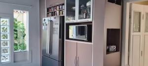 a kitchen with a refrigerator and a microwave at Quarto Pernoite Costa do Sol in Macaé