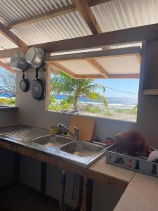eine Küche mit Spüle und Blick auf den Strand in der Unterkunft Faatiarau in Fakarava