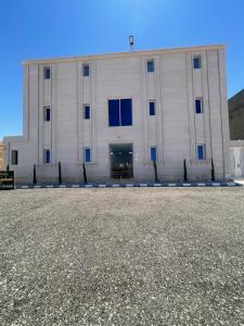 a large white building with blue windows in a parking lot at المجيدل للشقق المفروشة in Arar