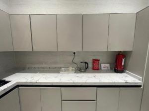 a kitchen counter with white cabinets and a red appliance at المجيدل للشقق المفروشة in Arar +8 photos