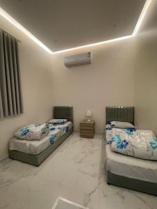 two twin beds in a room with marble floors at المجيدل للشقق المفروشة in Arar