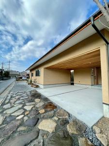 a house with a stone walkway next to a building at ファミリーロッジ つつじ in Sakaiminato