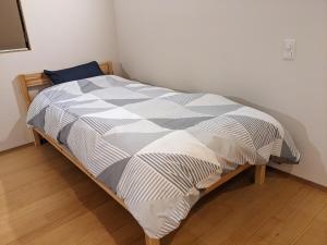 a bed in a room with a white and gray comforter at ファミリーロッジ つつじ in Sakaiminato