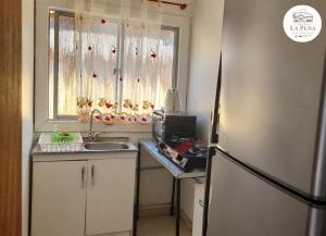 a kitchen with a sink and a refrigerator and a window at Cabañas nuevas La Peña in Taltal
