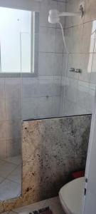 a bathroom with a glass shower with a toilet at Quarto Pernoite Costa do Sol in Macaé