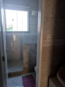a bathroom with a shower with a window and a sink at Quarto Pernoite Costa do Sol in Macaé