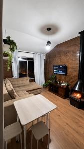 a living room with a couch and a table and a fireplace at Apartamento com Lareira a 5 Min da Feirinha do Alto - Piscina e Sauna in Teresópolis