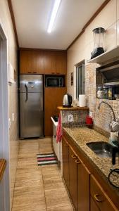 a kitchen with a stainless steel refrigerator and a sink at Apartamento com Lareira a 5 Min da Feirinha do Alto - Piscina e Sauna in Teresópolis