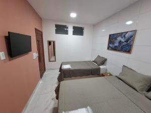 a room with two beds and a flat screen tv at Pousada Flor de Sal in Macau