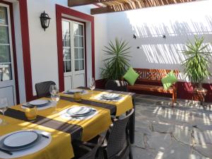 a dining room with two tables with yellow tablecloths at Tapada Poço das Canas in Redondo