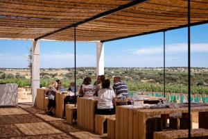 a group of people sitting at tables under a pergola at Tapada Poço das Canas in Redondo