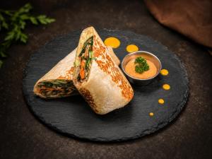 a sandwich on a black plate with a dipping sauce at Quepos Studio Apartments in Quepos