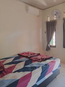 a bedroom with a bed with a colorful comforter at Sherin Homestay in Pulau Sarang