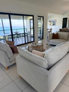 a living room with couches and a view of the ocean at The Dune House in Tangalooma +32 photos