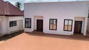 a white house with black doors and a brick floor at Antopom Heights & Suites in Sunyani