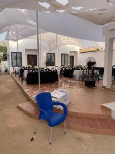 a blue chair in front of a room with tables at Antopom Heights & Suites in Sunyani