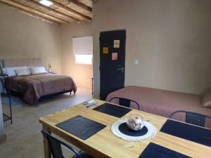 a room with two beds and a wooden table with a table sidx sidx at Dormis Talampaya in Villa Unión