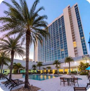 a hotel with tables and palm trees in front of a building at The Caloosa Retreat in Fort Myers