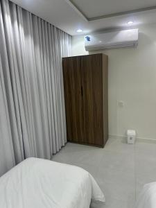 a bedroom with a bed and a wooden cabinet at شقة غرفتين وصالة in Musaylah