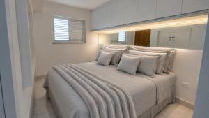 a white bedroom with a large bed with pillows at Recanto Veraneio - Londrina in Londrina +9 photos