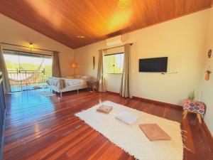 a living room with a bed and a television at Chalé Baru - Ar-cond - Varanda Pôr do Sol - Cavalcante Goiás in Cavalcante