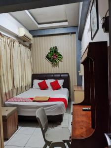 a bedroom with a bed with red pillows and a chair at Angs residence in Surabaya