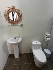 a bathroom with a toilet and a sink and a mirror at Studio confort Uvita in Uvita