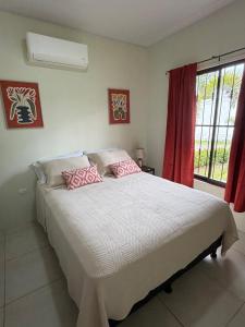 a bedroom with a bed with pink pillows on it at Studio confort Uvita in Uvita