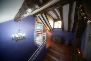 una escalera con una pared azul y una lámpara de araña en El Capricho de Nieves, en Laspuña