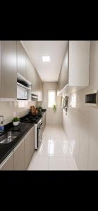 a white kitchen with a sink and a stove at Apartamento em Caruaru 3 quartos completo in Caruaru