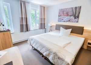 a bedroom with a large white bed and two windows at Hotel Waldhalle in Mölln +80 photos