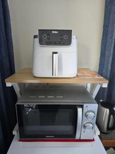 a microwave sitting on a shelf next to a toaster oven at Quiet Boutique Generous Breakfast in Palmerston North