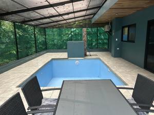 a swimming pool in a patio with chairs and a table at Las Pavitas Arenal Suites in Fortuna