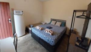 a bedroom with a bed and a refrigerator at Kitnet - quarto - privativo in Itupeva