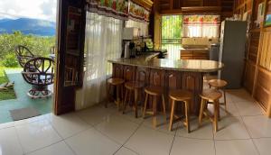 a kitchen with a island with stools and a counter top at Las Pavitas Arenal Suites in Fortuna