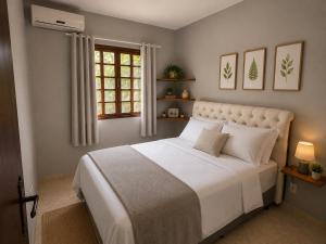 a bedroom with a white bed and a window at GH Pinheira in Palhoça
