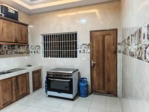 a kitchen with a stove and a wooden door at EmElla Manor in Komé
