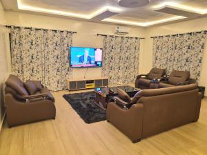 a living room with two couches and a flat screen tv at EmElla Manor in Komé