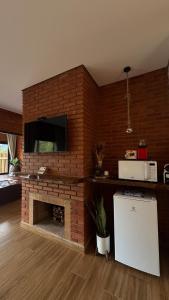 a living room with a brick fireplace with a tv at Chalé Raízes in Joanópolis