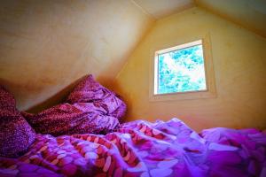 a bed with a purple comforter and a window at Walnussnest - Tiny House im Grünen in Bäbelin