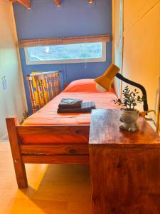 a bedroom with a bed and a table with a lamp at El Kamaruco Tiny House in El Chalten