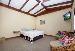 a bedroom with a bed and two wicker chairs at Hidden Valley Cabins & Tours in Coolbie