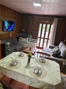 a living room with a table and a couch at Chalé cipreste 4 Quartos in Gramado