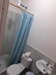 a bathroom with a toilet and a blue shower curtain at Mary Patsy House in Puerto López