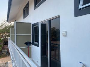 a white house with glass doors and a balcony at D'Alor Homestay in Pasir Mas