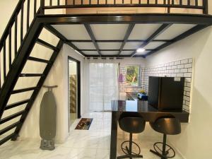 a room with a staircase with a television and stools at D'Alor Homestay in Pasir Mas