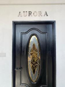 a black door with a window with the words aurora at D'Alor Homestay in Pasir Mas