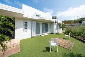 a white house with two chairs in the yard at The Mural Art House Bise in Motobu