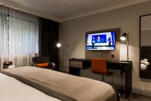 a hotel room with a bed and a desk with a television at Mercure Newcastle George Washington Hotel Golf & Spa in Newcastle upon Tyne